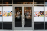the pizza press coming soon written on a glass door